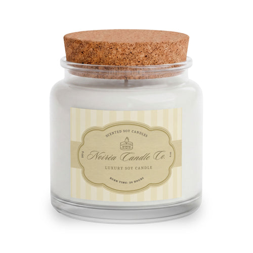 A Noiréa soy candle in a clear glass jar with white wax, a beige striped label, and a brown cork lid, shown on a white background.